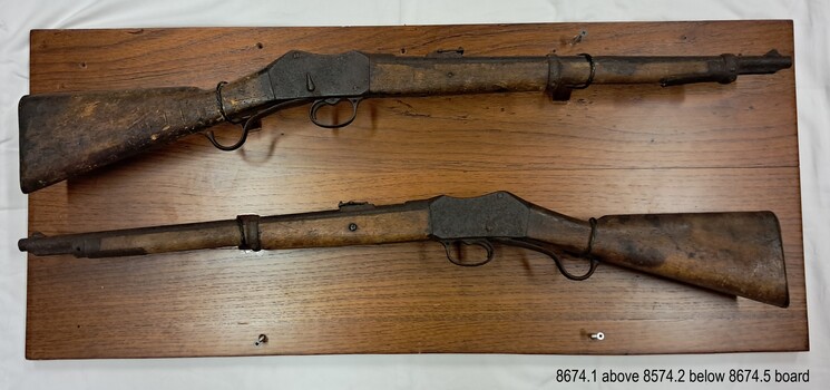 Two rifles mounted on a wooden board, one above the other