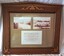 Wooden frame with glass front, containing two photographs and a document