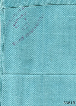 Pictured is the folded back view of a green woven surgical cloth. The linen service imprint is showing through from the front side. 