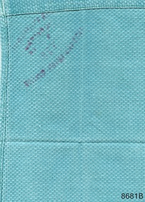 Pictured is the folded back view of a green woven surgical cloth. The linen service imprint is showing through from the front side. 