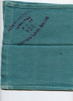 Folded view, right side up, of a green surgical cloth with hospital identification, showing the stamp of the hospital linen service in red. 