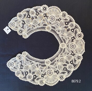 Round lace collar with flower motifs that include tulip shapes in groups of three. 