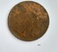 Round metal coin with a weathered figure on the face
