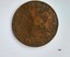 Round metal coin in a weathered condition with two lines of writing around the edge