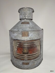 Front of upright metal lamp with ribbed glass front, inscription plaques