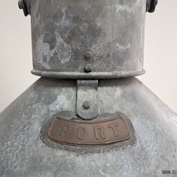 Close-up of the top crescent-shaped brass plaque on the lamp