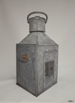Reverse of lamp, top handle up, side panel with handle, other panel with fitting