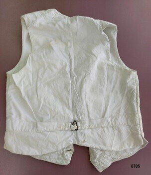 Back of cream cotton waistcoat with fabric strap and metal buckle.
