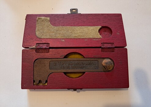 Red wooden box with fitted cutout inside for key spanner