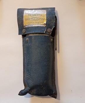 Black leather pouch with flip up opening, containing a metal object