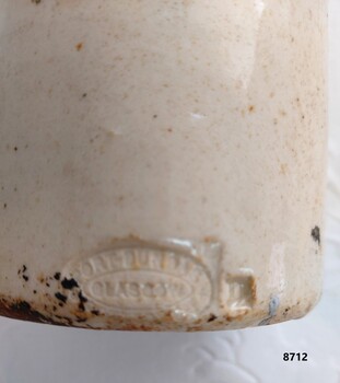 Oval shaped stamp with Makers' name and location on bottom side of bottle.