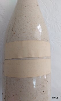 Two pieces of tape on side of bottle with faint writing.