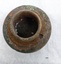 Cylindrical brass fitting with round 2 cm high threaded shank, rusted washer and a 2 cm wide flange above an octangular, flat cap.