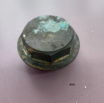 Cylindrical brass fitting with flat, octagonal cap above a 2 cm, round flange.