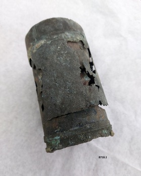 Cylindrical metal tube with verdigris colouring and a corroding, unstable surface. One end has a fine threaded rim.