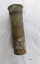Cylindrical brass tube with slightly flared cap at one end. There is an indistinct mark (like an "8") just above an outer layer of metal that has flaked off.