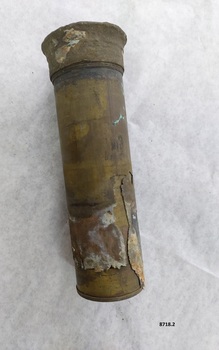 Cylindrical brass tube with slightly flared cap at one end. There is an indistinct mark (like an "8") just above an outer layer of metal that has flaked off.