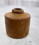 Brown clay inkpot with straight sides and small circular opening in the top. Some small dents and staining show on the surface of the sides.