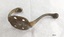 Metal coat hook with two prongs and four screw holes with a surface showing rust and corrosion.