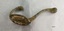 Brass coat hook with two prongs and four screw holes with a surface showing extensive green and brown oxidation.