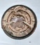 Circular iron frame encasing a heavily encrusted internal frame with three metal lugs and thick, round, domed glass.
