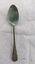 Front of silver tablespoon with green patina on base of "bowl" and neck of spoon.