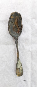 Front of dessert spoon, with fiddle back handle. Has green and black tarnish and the bowl is heavily encrusted.