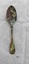 Front of dessert spoon, with fiddle back handle. Has green, purple and brown tarnish and corrosion.