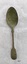 Back of dessert spoon with fiddle back handle. The thin metal has several small holes and is slightly encrusted with green and brown tarnish.