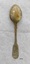 Spoon with fiddle back design on both ends of handle. It has silver marks stamped on handle and is displaying brown oxidation.