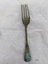 Large dinner fork with green patina on end of handle and tines.