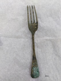 Large dinner fork with green patina on end of handle and tines.