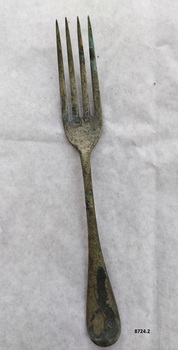 Dessert fork with rounded handle and some black and green tarnish.