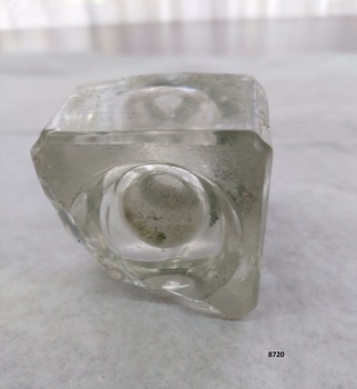 Underneath of a square glass inkwell with concave indentation in base.