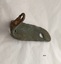 The narrow short outer side of an L shaped metal plate with one made hole showing a coating of green verdigris and a flaking layer of rust.