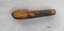 The wooden handle of the pocket knife has much of the outer veneer missing, exposing the lighter wood underneath.