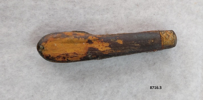 The wooden handle of the pocket knife has much of the outer veneer missing, exposing the lighter wood underneath.