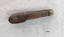 Side of pocket knife with brown wooden handle and metal cap showing some corrosion.
