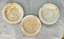 Three chalky white plates - two with brown staining and two with chipped rims.
