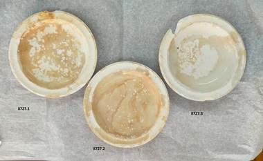 Three chalky white plates - two with brown staining and two with chipped rims.