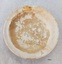View of top of plate 8727.1 showing brown staining, patchy glaze and chip in rim.