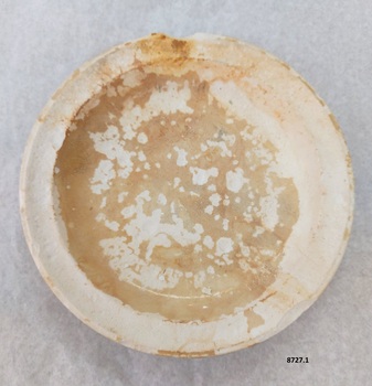 View of top of plate 8727.1 showing brown staining, patchy glaze and chip in rim.