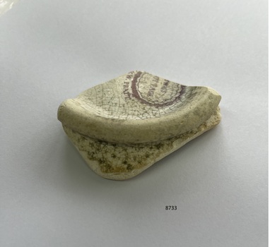 Fragment of china with partial manufacturer's stamp and raised curved edge.