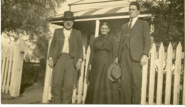 Two men and a woman outside a house