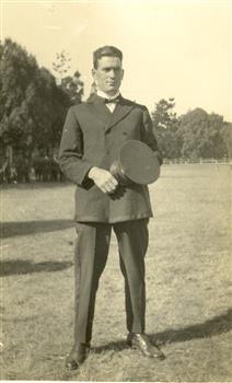 Frank Wright stands holding his cap. 