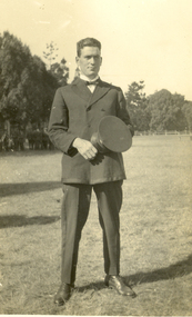 Frank Wright stands holding his cap. 