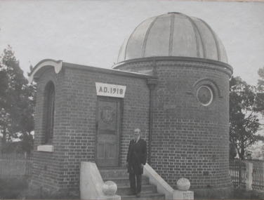 A man on the steps of an observatory