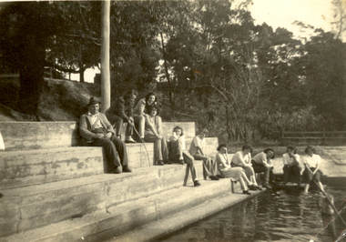 Swimming pool with people sitting around it. 