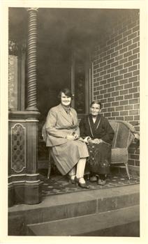 Two women sit on a verandah