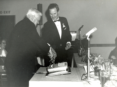 Photograph - Black and White, Albert E. Stohr cuts the Ballarat School of Mines Centenary Cake watched on by Jack Barker, 1970, 08/08/1970
